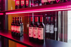 Detailaufnahme von Tignanello-Weinflaschen unter pinkem LED-Licht.