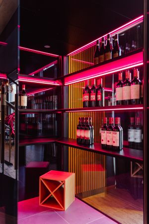 Blick durch die beleuchtete Weinvitrine auf den Gastraum.