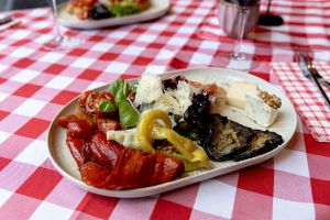 Nahaufnahme eines Antipasti-Tellers mit Bruschetta, gegrillter Paprika, Aubergine, Artischocke, Peperoni, gehobeltem Parmesan, Salami und Blauschimmelkäse.