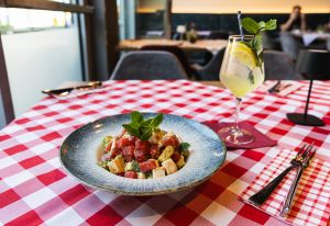 Ein bunter Salat aus gewürfelter Wassermelone, Avocado und weißem Käse, garniert mit Minzblättern in einem tiefen Teller.